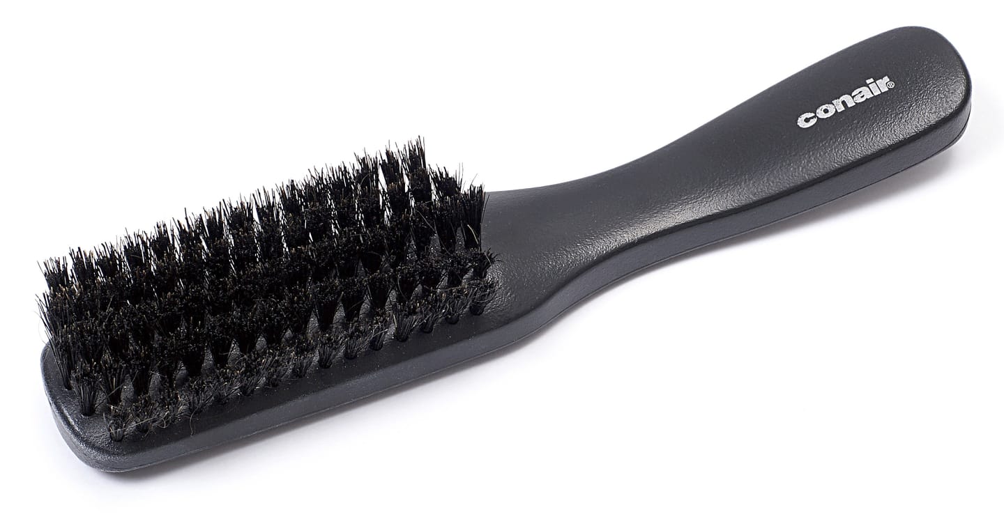Eine schwarze Haarbürste mit Naturborsten vor hellem Hintergrund