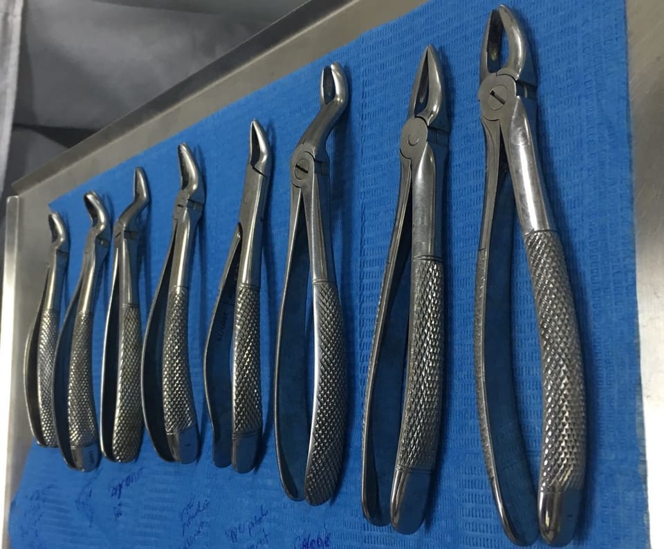 Mehrere Zahnextraktionszangen in unterschiedlichen Formen auf einem blauen Tuch