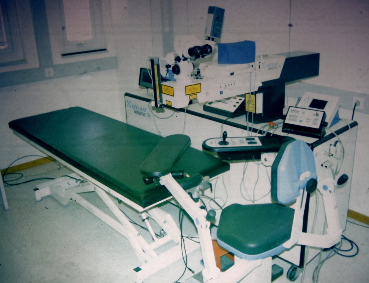 Eye laser treatment room with an excimer laser on a stand next to a patient couch and no one present