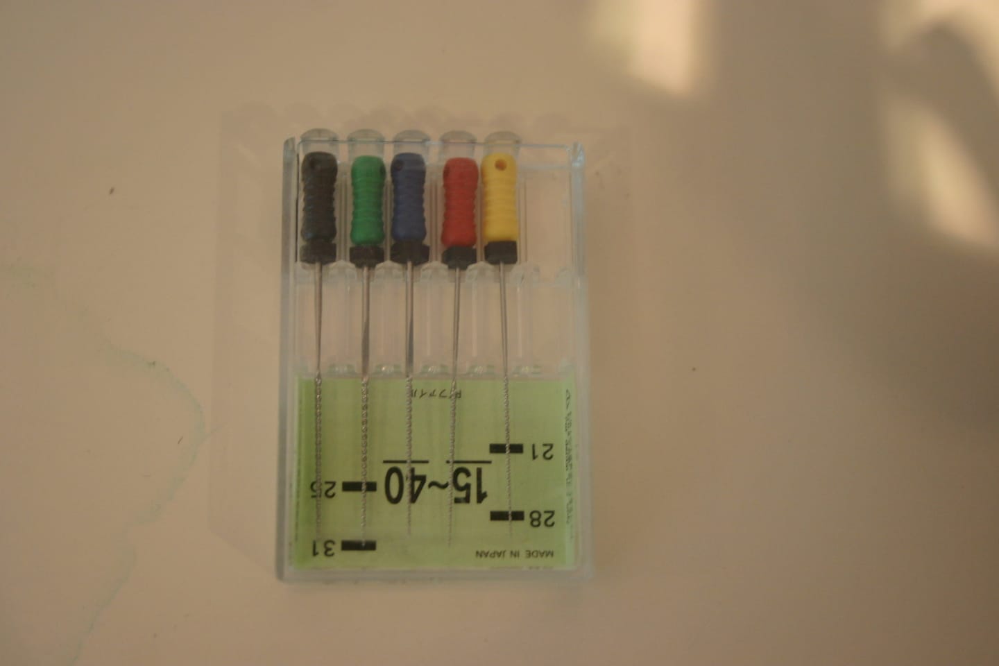 Set of five colour-coded endodontic files used to clean root canals in their packaging, with size markings